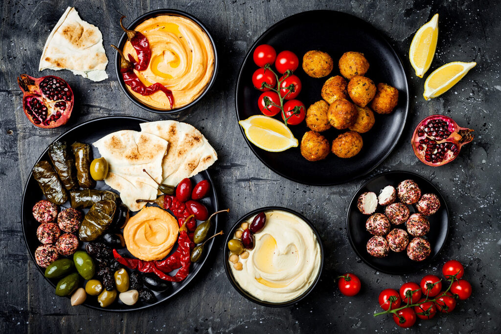 Middle Eastern meze platter with pita, olives, hummus, stuffed dolma, labneh cheese balls in spices.