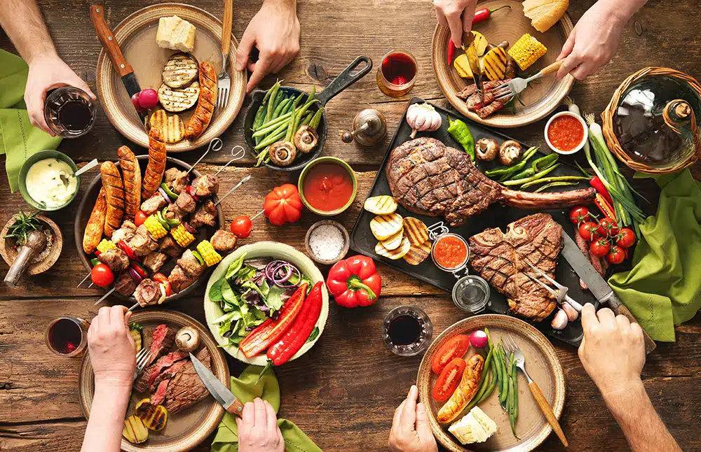 top-view-image-of-group-of-people-enjoying-grilled-meats-and-grilled-vegetables-with-custom-sauces-on-a-table