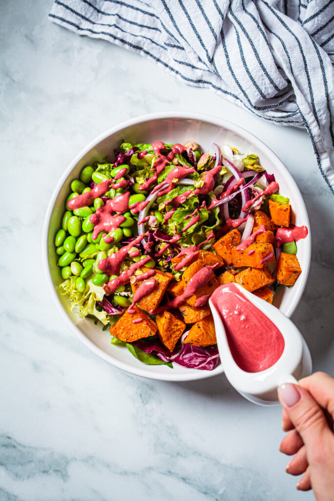 Vegan-salad-bowl-with-baked-sweet-potatoes-edamame-beans-nuts-and-pink-beetroot-dressing