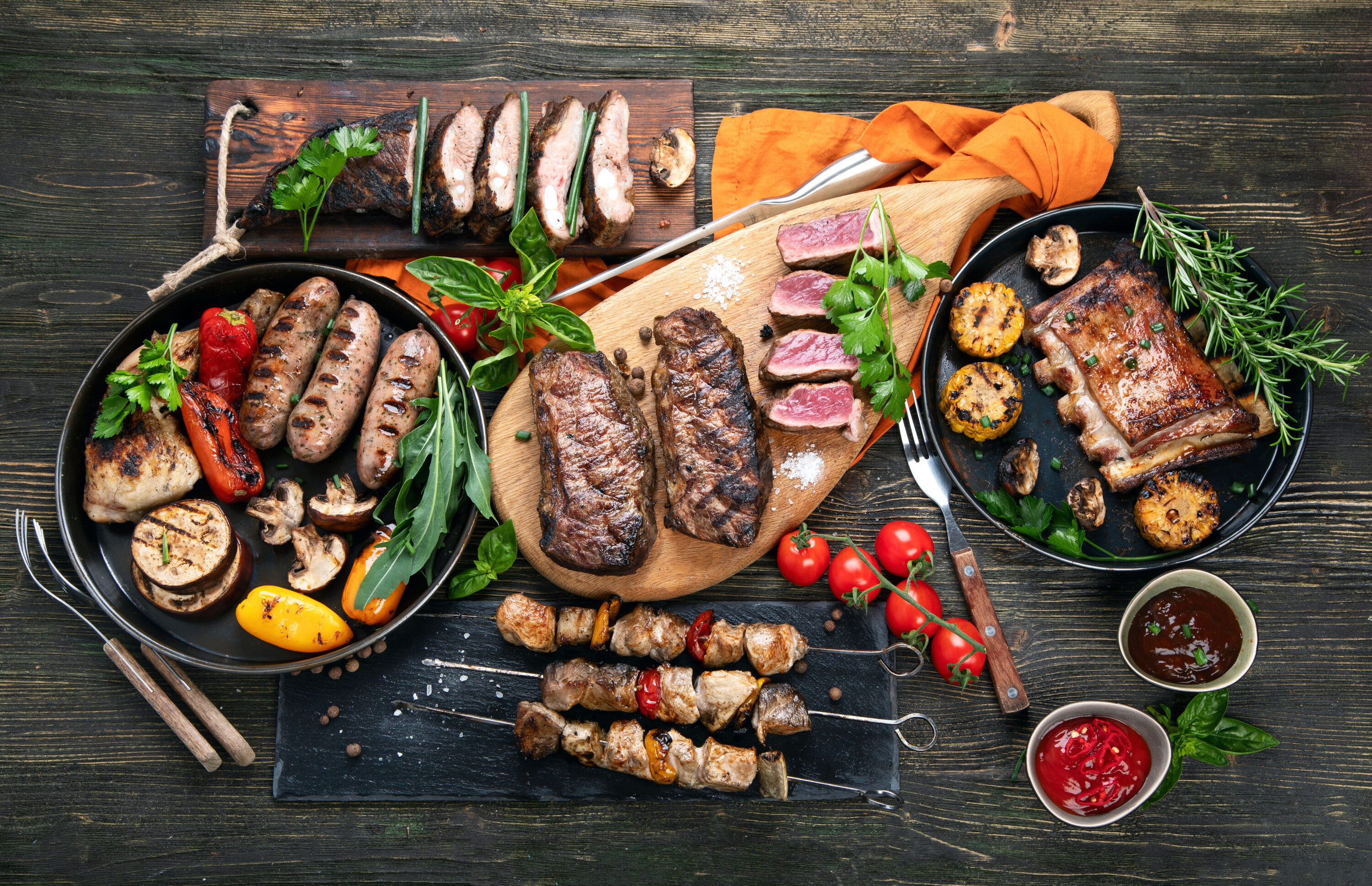 assorted-meat-with-vegetables-on-wooden-background-barbecue-with-sauces-in-dip-cups