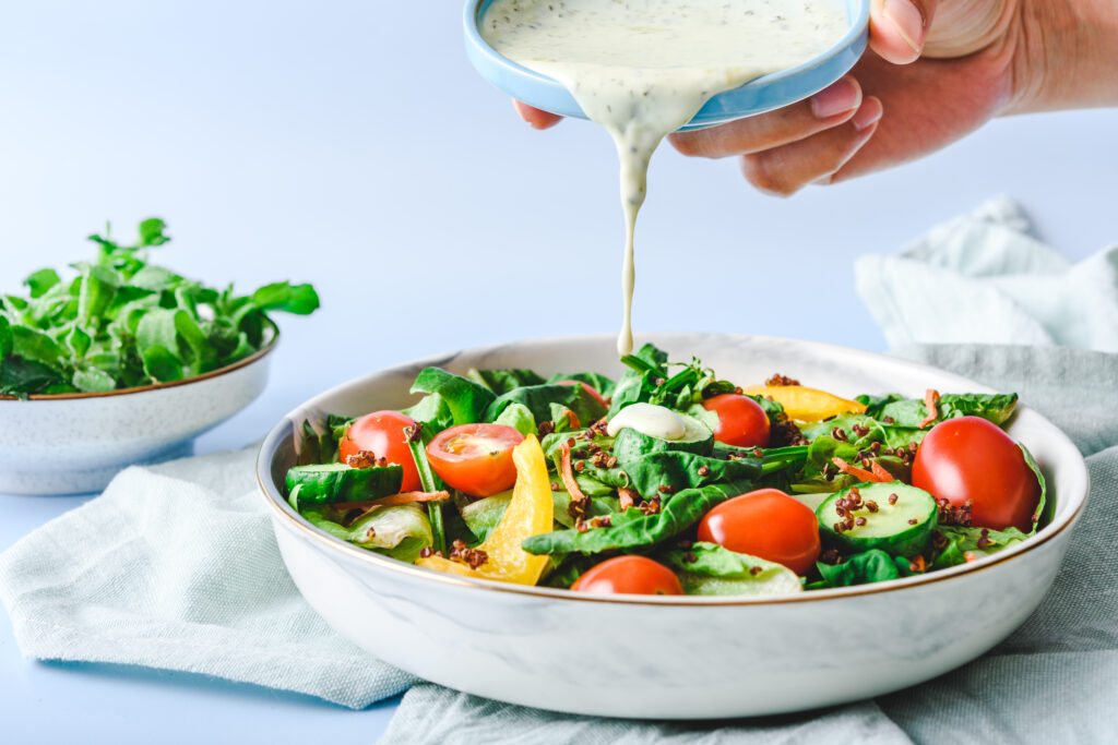 pouring-dressing-on-garden-salad-on-a-light-green-cloth