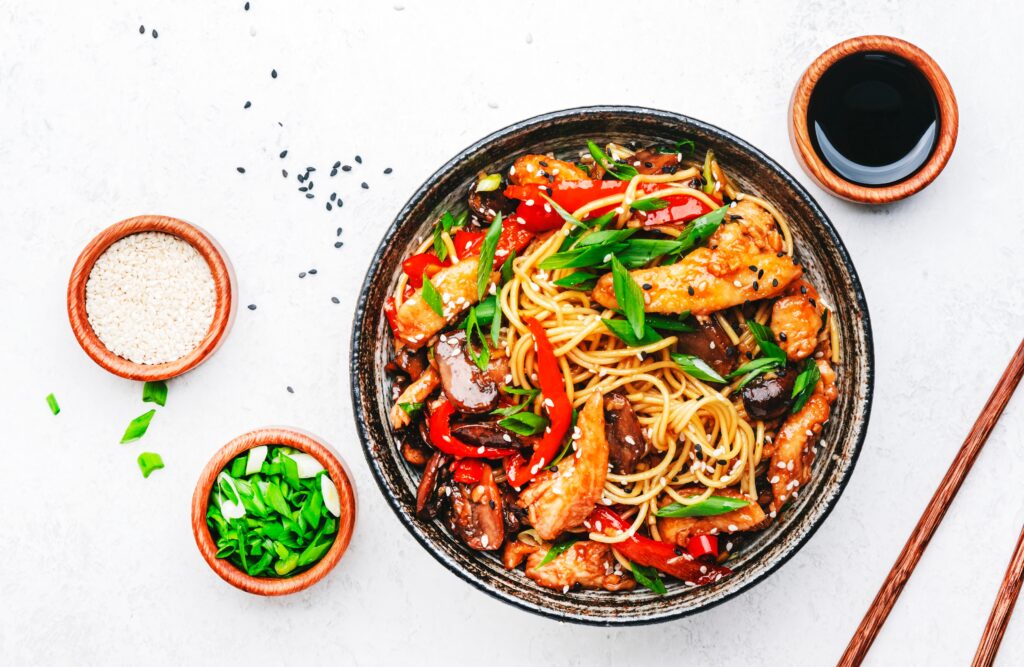 stir-fry-egg-noodles-with-chicken-sweet-paprika-mushrooms-chives-and-sesame-seeds-in-bowl-asian