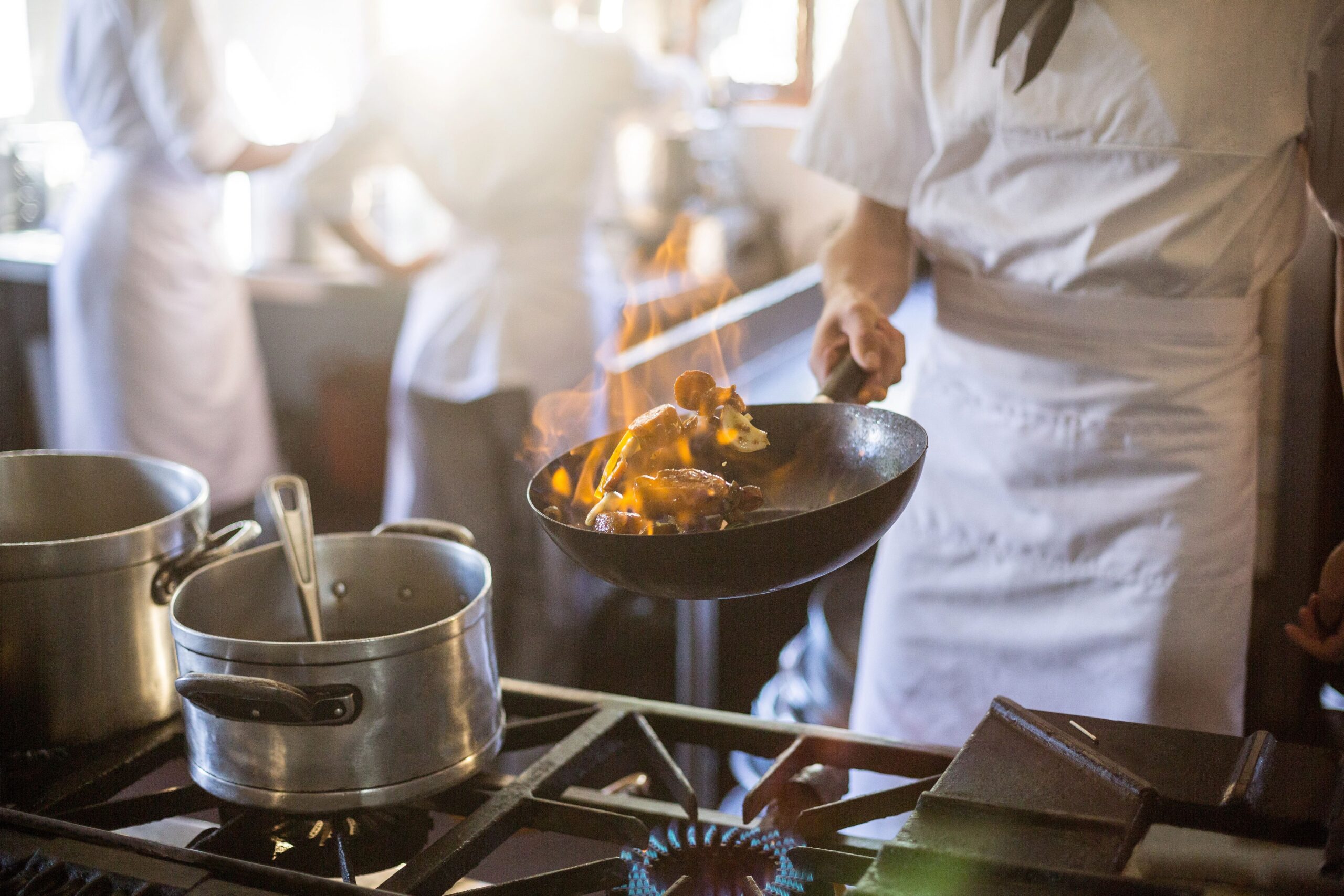 Chef cooking, holding pan over stove