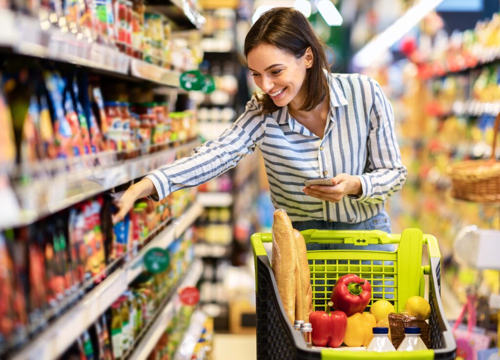 Smiling young woman shopping for sauces at grocery store
