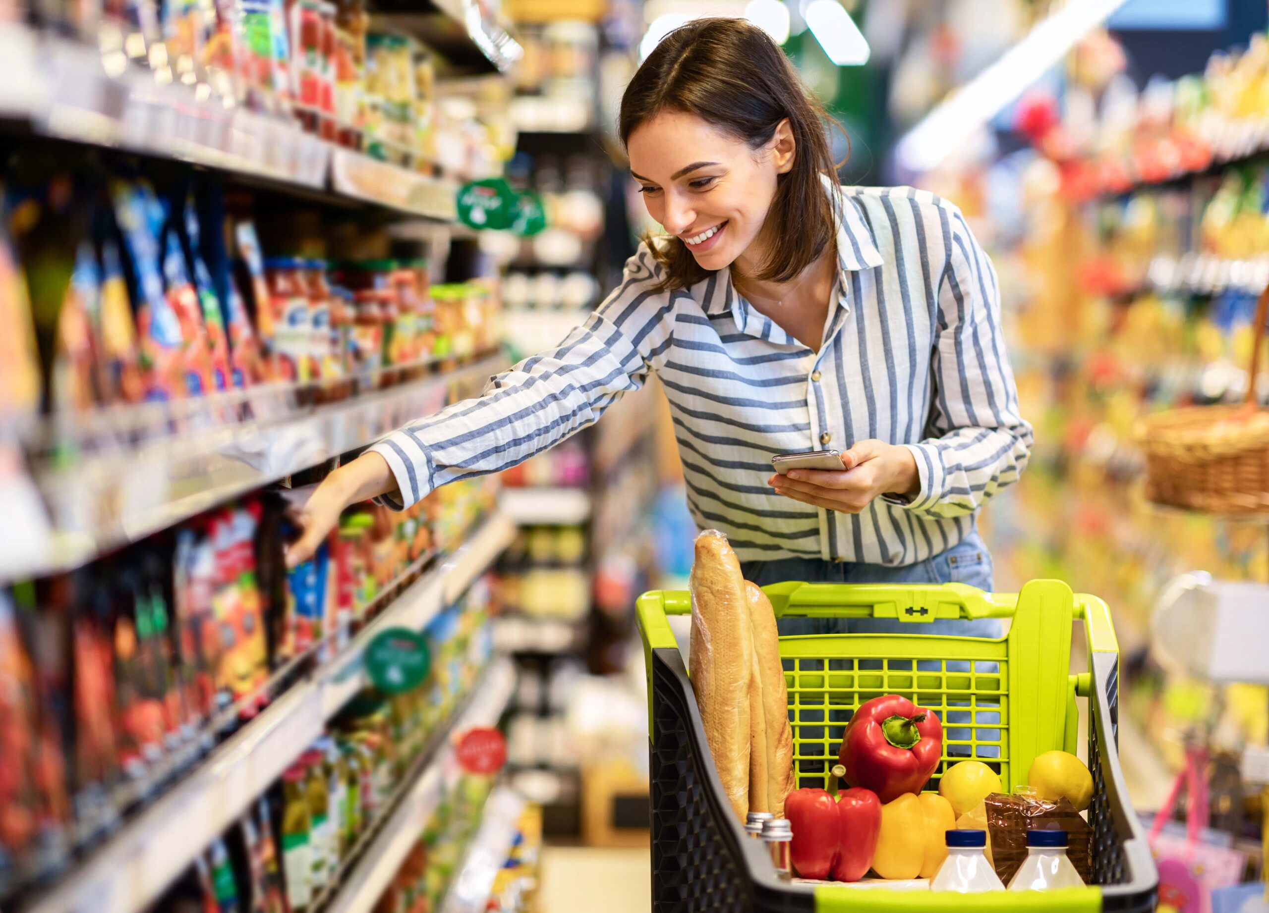 Smiling young woman shopping for sauces at grocery store