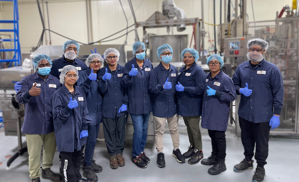 Giraffe Foods Team in front of sauce manufacturing equipment