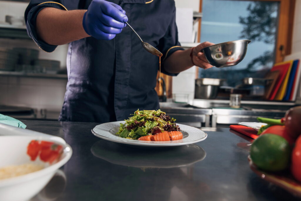 Chef pouring sauce onto salad