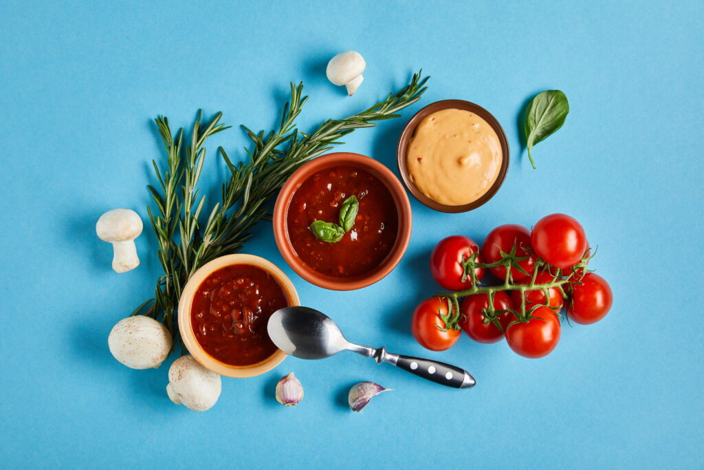 Three sauces in small bowls, tomatoes, rosemary, mushrooms, garlic