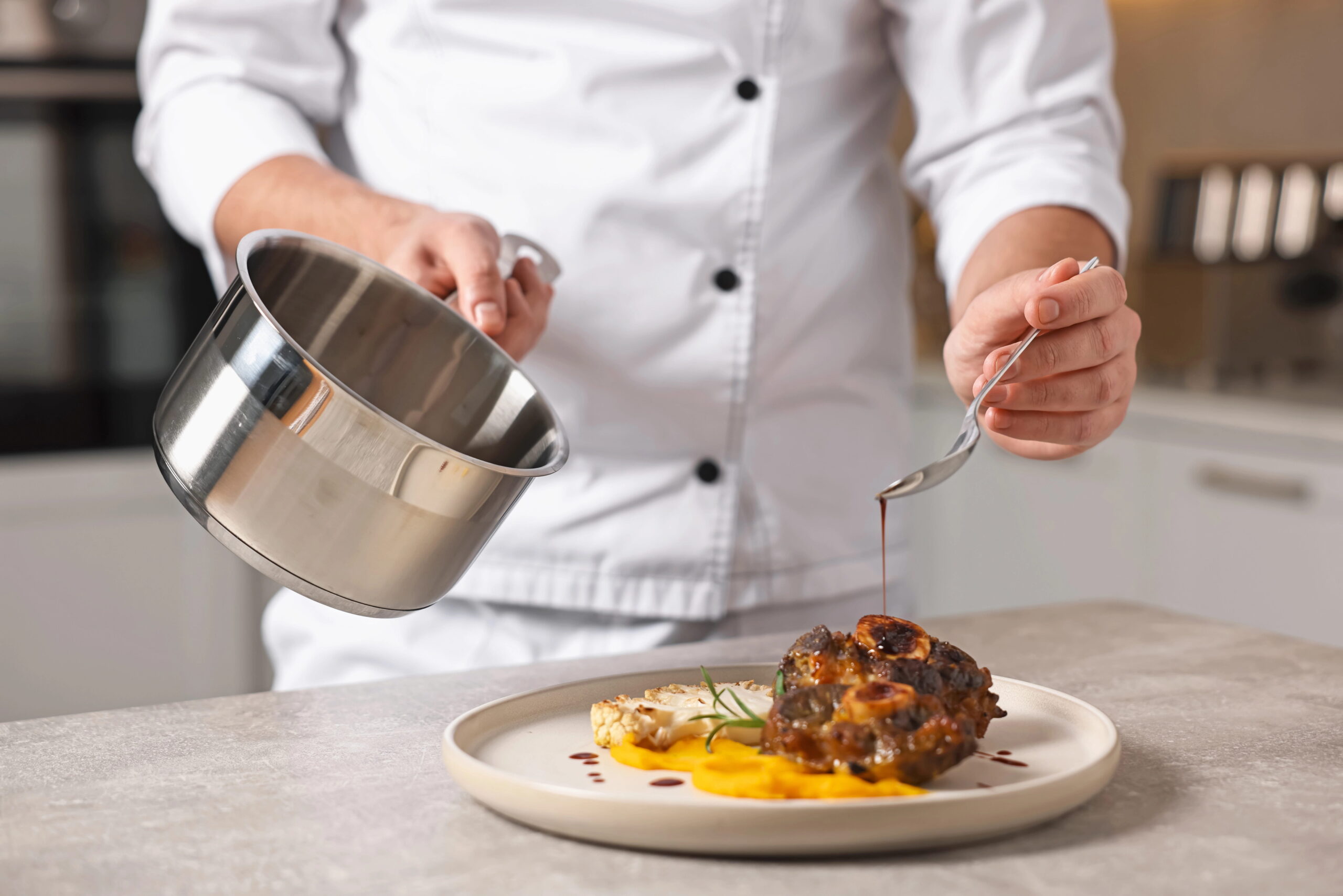 Chef pouring sauce over delicious dish